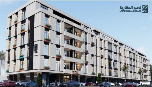 Front-facing view of a multi-story residential building with balconies, palm trees, and street-level shops.